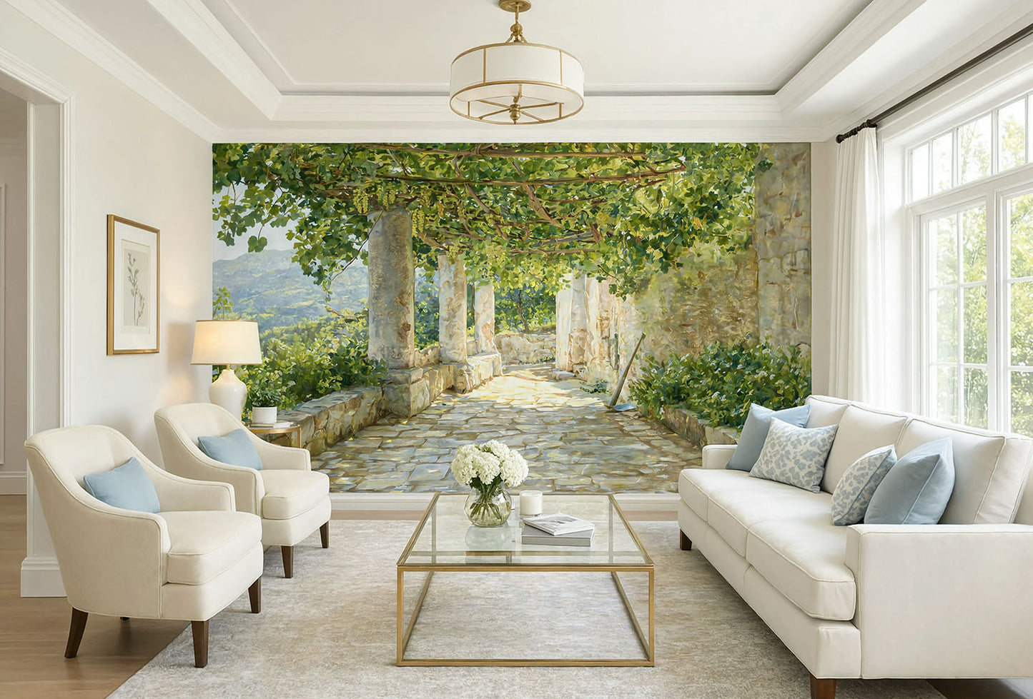 Large panoramic vintage wallpaper mural of a sunlit Italian terrace with stone pillars, green leaves casting shadows, and distant mountains in the background.
