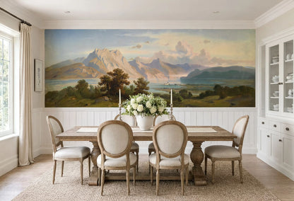 Panoramic vintage wallpaper mural featuring an alpine lake and majestic mountains above white wainscoting panels.