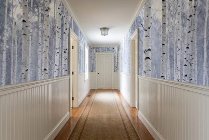 A hallway with birch tree wallpaper on the upper walls, white beadboard wainscoting.