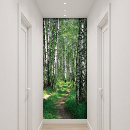 A wall mural depicting a lush green birch forest path, shown installed on a hallway wall between white doors.