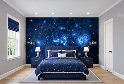 A modern bedroom featuring a dramatic dark blue galaxy starry wall mural as the focal point, styled with a matching navy blue bedspread, pillows, and two matching nightstands.