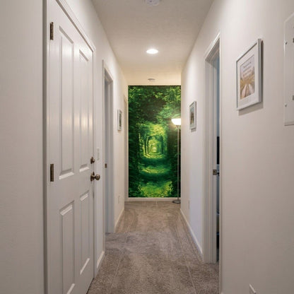 A hallway with white doors and walls, carpeted floor, and a large green forest mural or wallpaper at the far end.