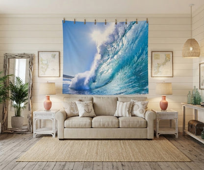 A large wall tapestry featuring a dramatic blue ocean wave crashing, displayed in a styled living room above a beige sofa with decorative pillows.