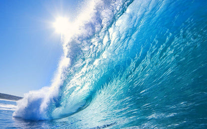 Large blue ocean wave with white foam against a clear sky