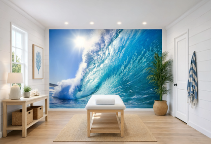 A large wall mural depicting a powerful curling ocean wave with bright sunlight and white foam, installed on a white shiplap wall in a bright, modern room with a wooden bench, side table, and potted plant.