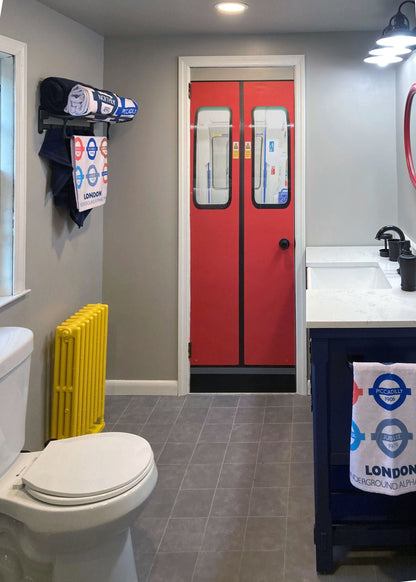 Bathroom with red doors, yellow radiator, and London-themed decor