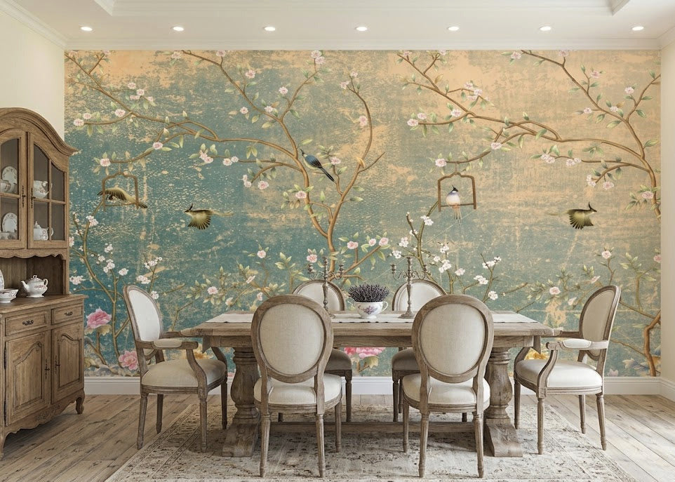 A dining room featuring a large wall mural with a vintage-style floral and bird design in muted teal, beige, and pink tones.