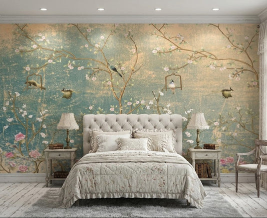 A styled bedroom featuring a large wall mural with a vintage-style floral and bird design in soft teal, beige, and pink tones.