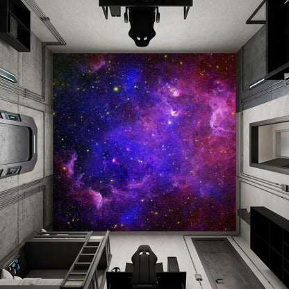A large wall mural featuring a vibrant purple and blue galaxy nebula with pink clouds and countless small stars, displayed on a wall in a modern, industrial-style room with a gaming chair and desk.