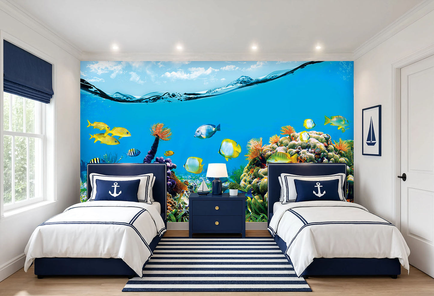 A styled children's bedroom featuring a large, vibrant underwater ocean wall mural with colorful fish and coral reefs behind two single beds with white and navy bedding.